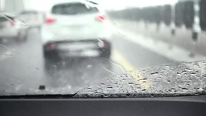 汽车雨刮器正在缓慢清除雨水并在道路上行驶