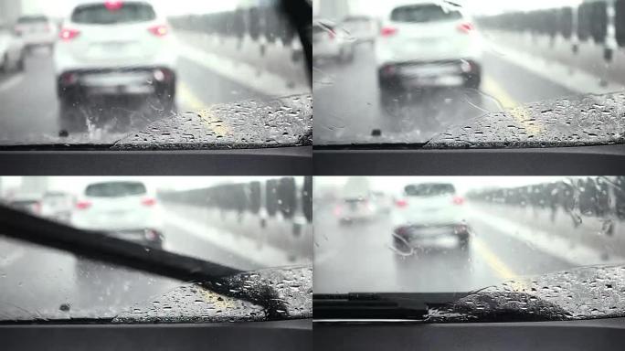 汽车雨刮器正在缓慢清除雨水并在道路上行驶