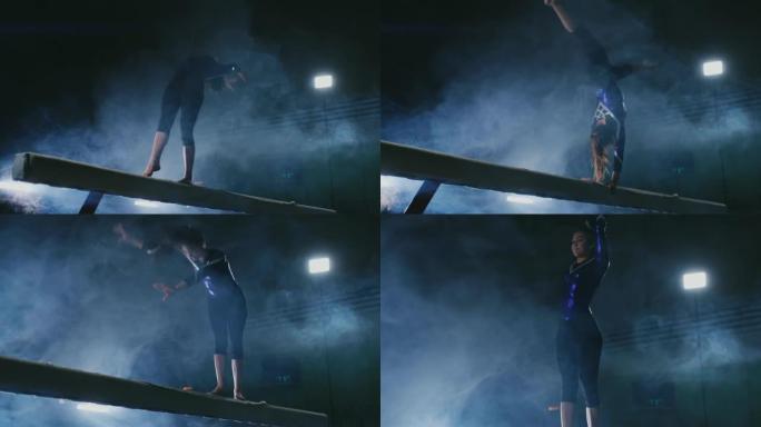 腿专业女孩体操运动员在平衡木上的烟雾中慢动作跳跃。女子艺术体操
