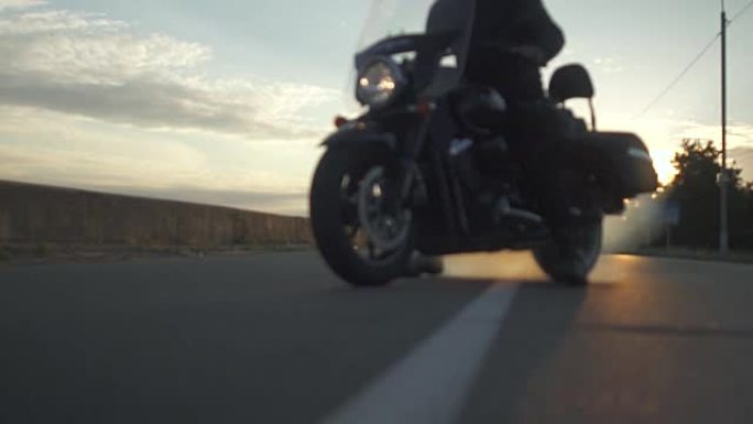 骑摩托车的人在日落时在道路上制造大量烟雾，慢动作