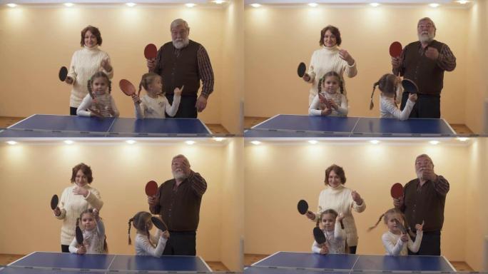 祖父母带着可爱的小孙女准备打网球，等待一拳。