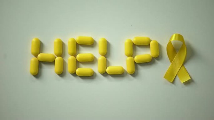 女性放黄丝带，桌上用药丸做的帮助字，儿童癌症
