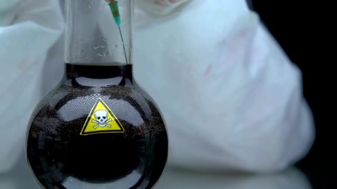 化学家在注射器中吮吸深色有毒液体，致命液体的发展