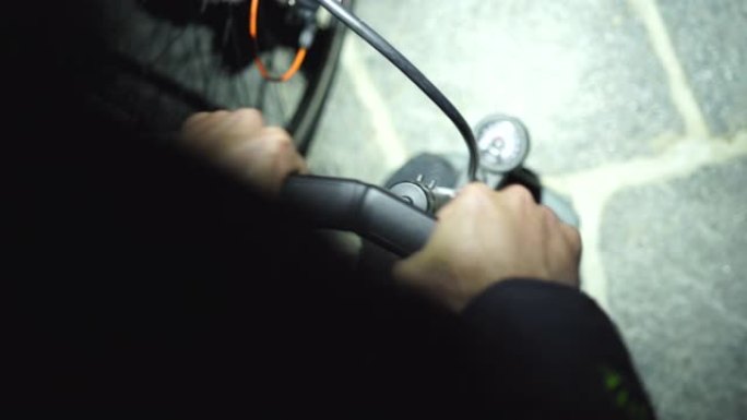 骑自行车的人在黑暗中用前照灯将空气泵入轮胎