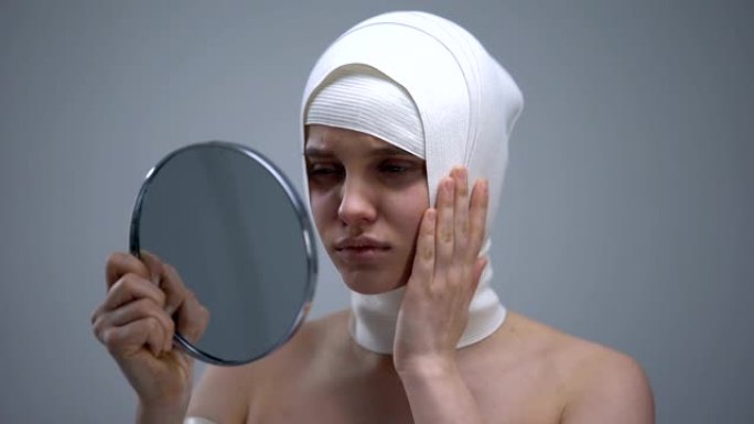 女性穿着弹性头套照镜子，整容后感到疼痛