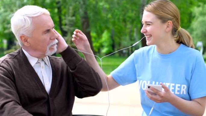 女志愿者给孤独的老人送耳机，在公园听音乐