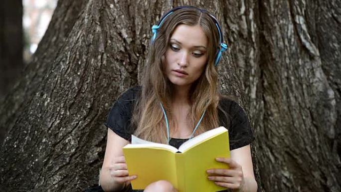 戴着耳机的女孩在公园看书