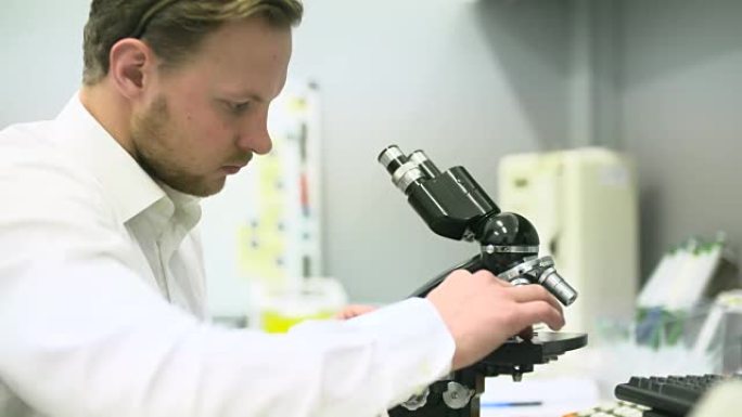 科学家正在通过显微镜观察并在平板电脑上写入数据。