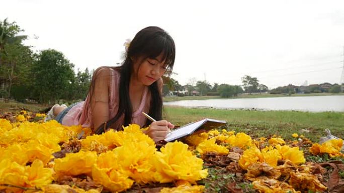 亚洲女孩躺在草地上读书