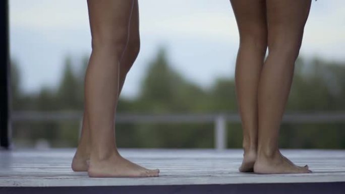 两对跳舞的细长晒黑的女性腿。一个周末，女孩们在游泳池附近的休息室玩得开心