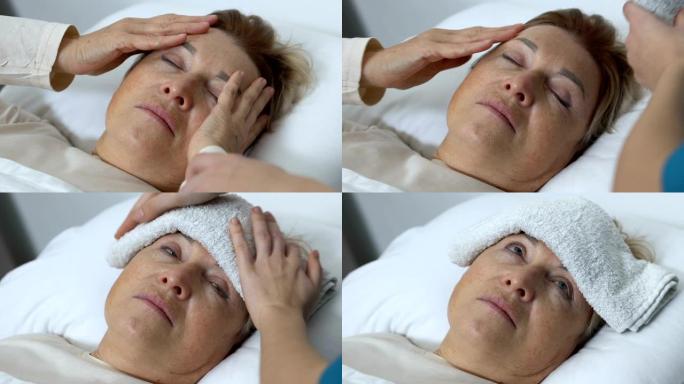 自愿者将湿毛巾放在高龄妇女额头上，头痛治疗，护理