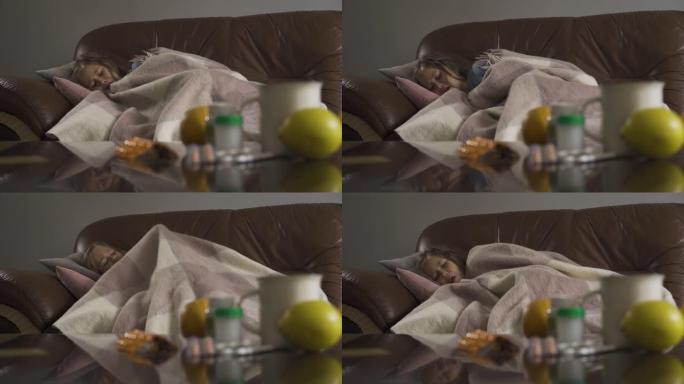 咳嗽的小女孩躺在背景上，桌子上放着药丸，柠檬和一杯茶。