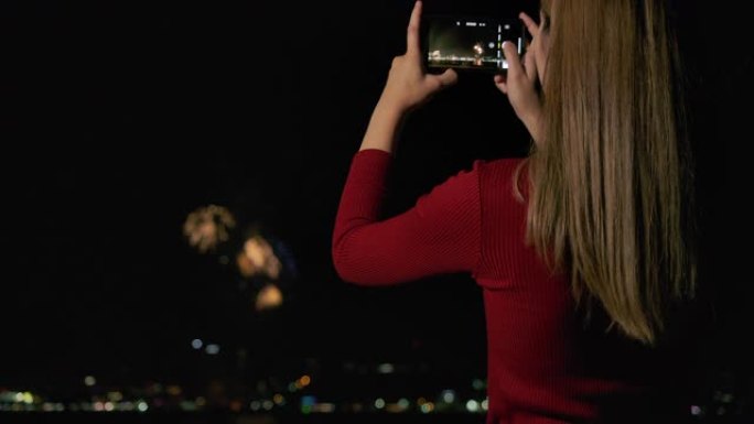4k新年节亚洲女性她在年底庆祝活动中使用手机拍摄烟花。
