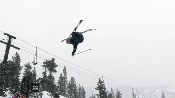 在一个下雪的阴天，科罗拉多州博尔德附近的埃尔多拉滑雪胜地，一名穿着完整冬季装备的滑雪者在森林和滑雪缆