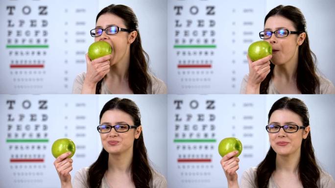戴着眼镜的微笑女士咬着新鲜的苹果，健康的营养，天然维生素