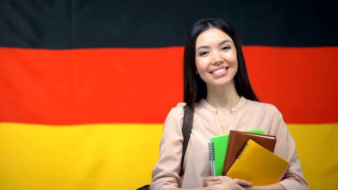 快乐的女学生拿着反对德国国旗背景的字帖，教育