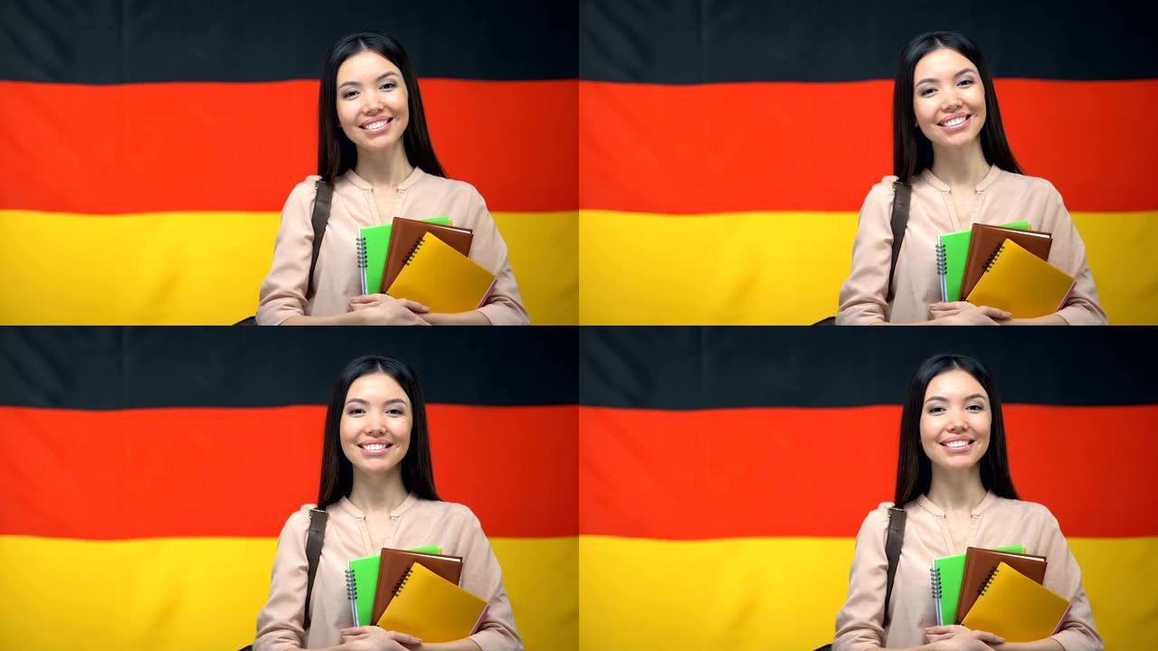 快乐的女学生拿着反对德国国旗背景的字帖，教育