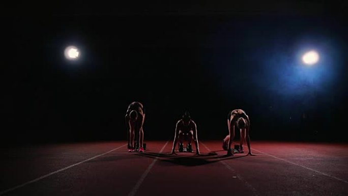 田径比赛的女跑步者在比赛前蹲在起跑区。慢动作