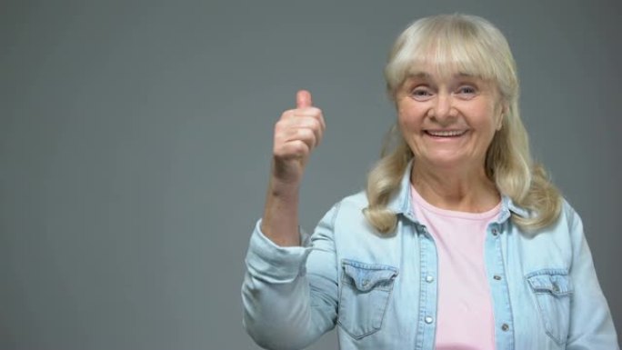 满意的老年妇女表现出竖起大拇指的手势，快乐的医疗诊所病人