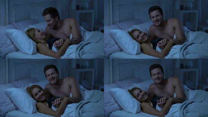快乐的微笑夫妇躺在床上，看着镜头，解决家庭问题，广告