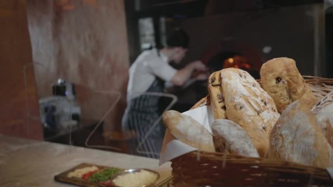 新鲜出炉的面包躺在篮子里，在现代餐厅的桌子上的前景特写。