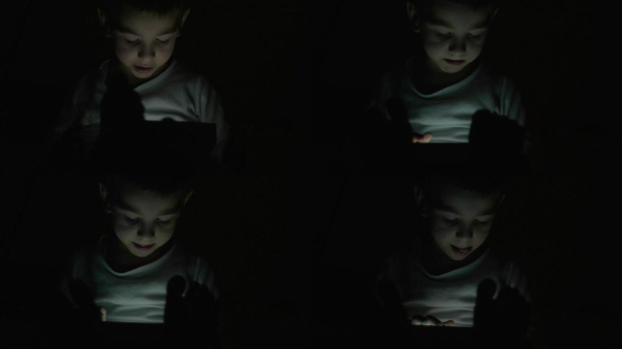 小男孩晚上在平板电脑上玩游戏