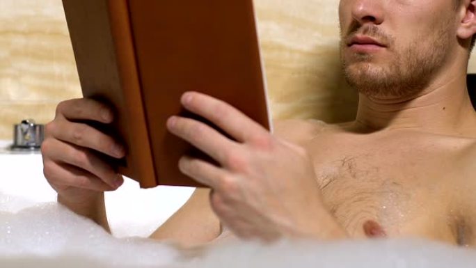 浴缸里帅气的男性阅读书，爱好和茶点，自由活动