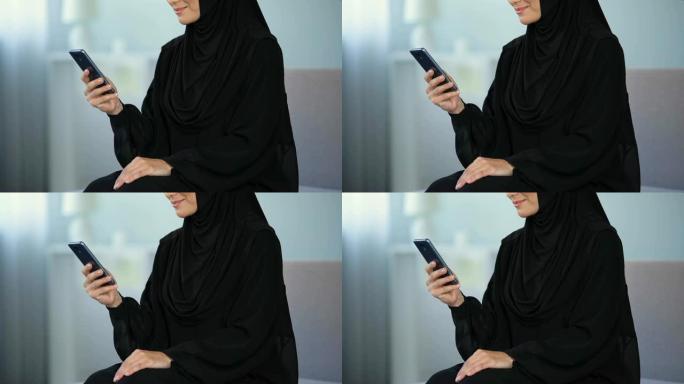 微笑的阿拉伯妇女阅读智能手机信息，在线交流，聊天
