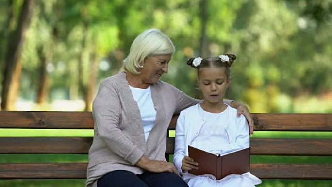 小孙女向祖母大声朗读，在公园里消遣