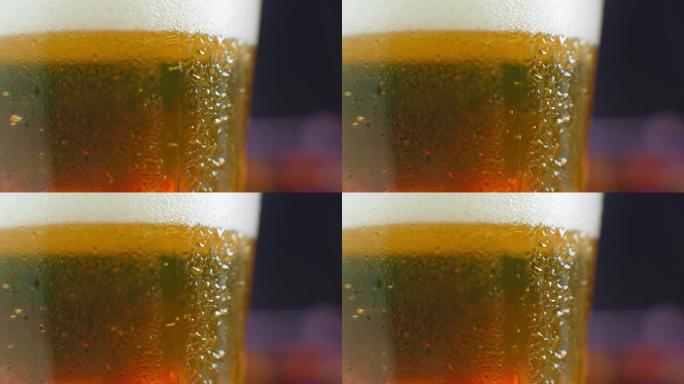 一滴啤酒在一杯啤酒上的微距镜头。一杯冷啤酒上流汗。滴在装满啤酒的玻璃杯上