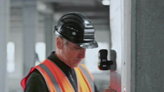 高加索男性建筑师使用带有激光测量的水平仪测量墙壁