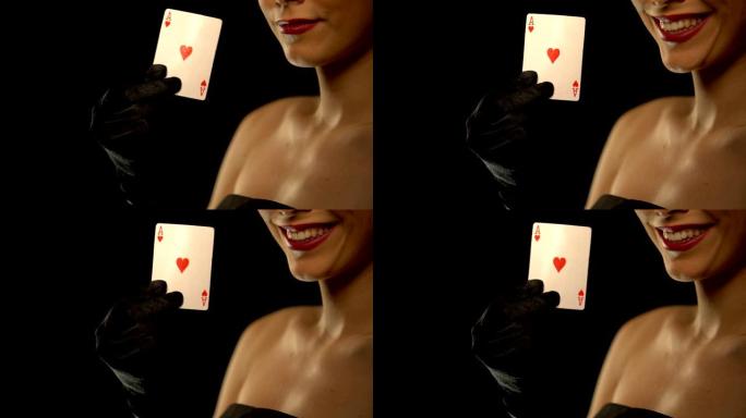 微笑的女人向镜头展示红心a，孤立在黑色背景上