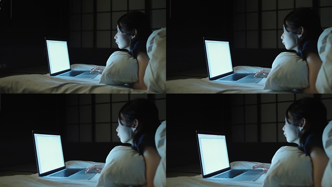 日本妇女在床上使用笔记本电脑