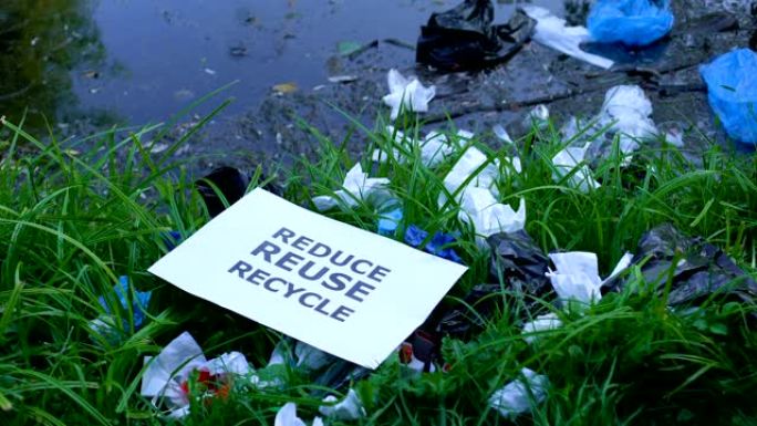 人在污染的草地上扔纸板减少重复使用回收短语