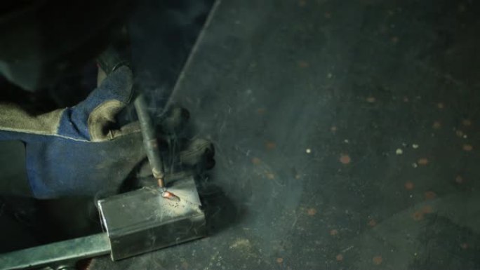 火花飞舞时，直接在车间的金属焊接台上进行人MIG焊接的头顶射击