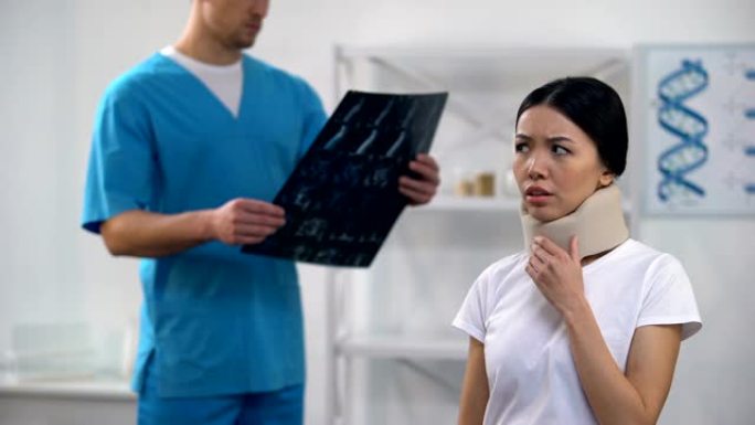 男性创伤学家看着泡沫颈圈的颈部x光检查女士感觉不好