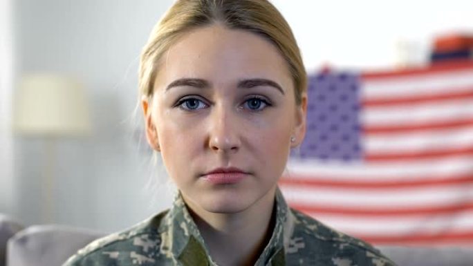 一名悲伤的女兵看着背景是美国国旗的摄像机，这是阵亡将士纪念日
