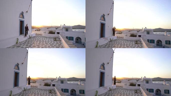 女人在白色希腊城市享受日落