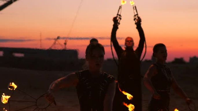 烈火舞者在日落时。一名年轻女子在舞蹈表演中与火圈对着日落摆姿势。
