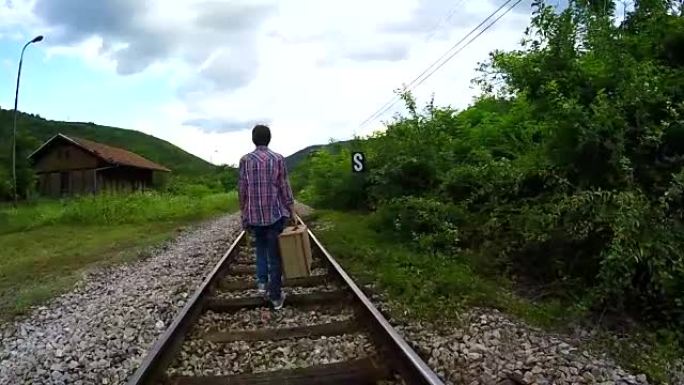 站在铁路上的复古手提箱的男人