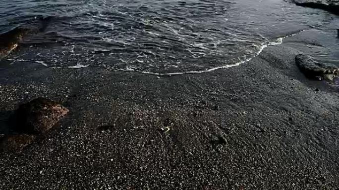 高清: 海浪在印度尼西亚巴厘岛黑沙海滩的沙滩上坠落