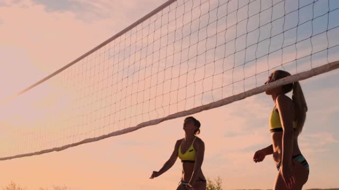 一群年轻女孩在日落或日出时打沙滩排球。