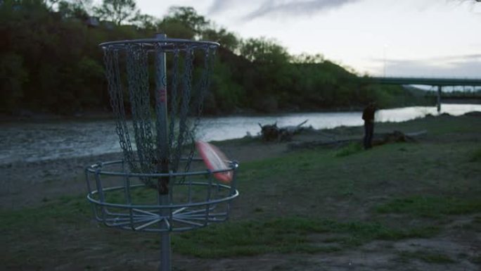 日落时，在科罗拉多河旁的圆盘高尔夫球场 (飞盘高尔夫)，一名男子用反手推杆将圆盘高尔夫推杆扔进未耕种