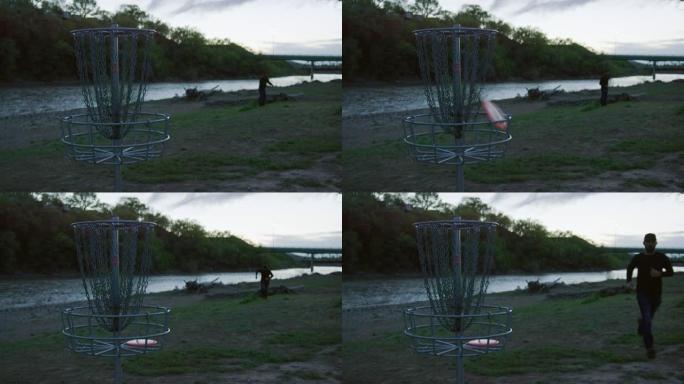 日落时，在科罗拉多河旁的圆盘高尔夫球场 (飞盘高尔夫)，一名男子用反手推杆将圆盘高尔夫推杆扔进未耕种