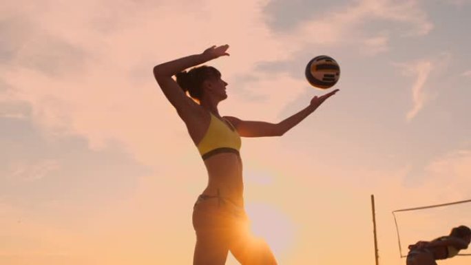 沙滩排球发球-女子在沙滩排球比赛中发球。上手扣球发球。年轻人在阳光下玩得开心，在户外健康积极的运动生