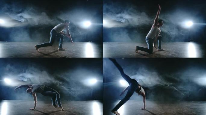 男舞者在聚光灯下的烟雾中表演了一个特技跳跃，并在场景中旋转了一圈。现代芭蕾。