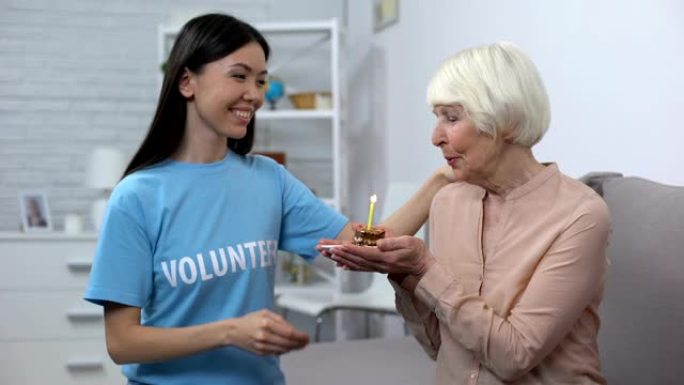 微笑的志愿者向养老院的高级养老金领取者赠送生日蛋糕