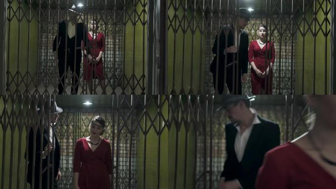 穿着西装和帽子的高个子男人打开门，在黑暗的房间里经过一个穿着优雅红色连衣裙的自信漂亮的女孩。