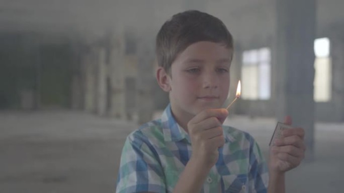 一个可爱的男孩站在烟熏房间里放火烧火柴的肖像。