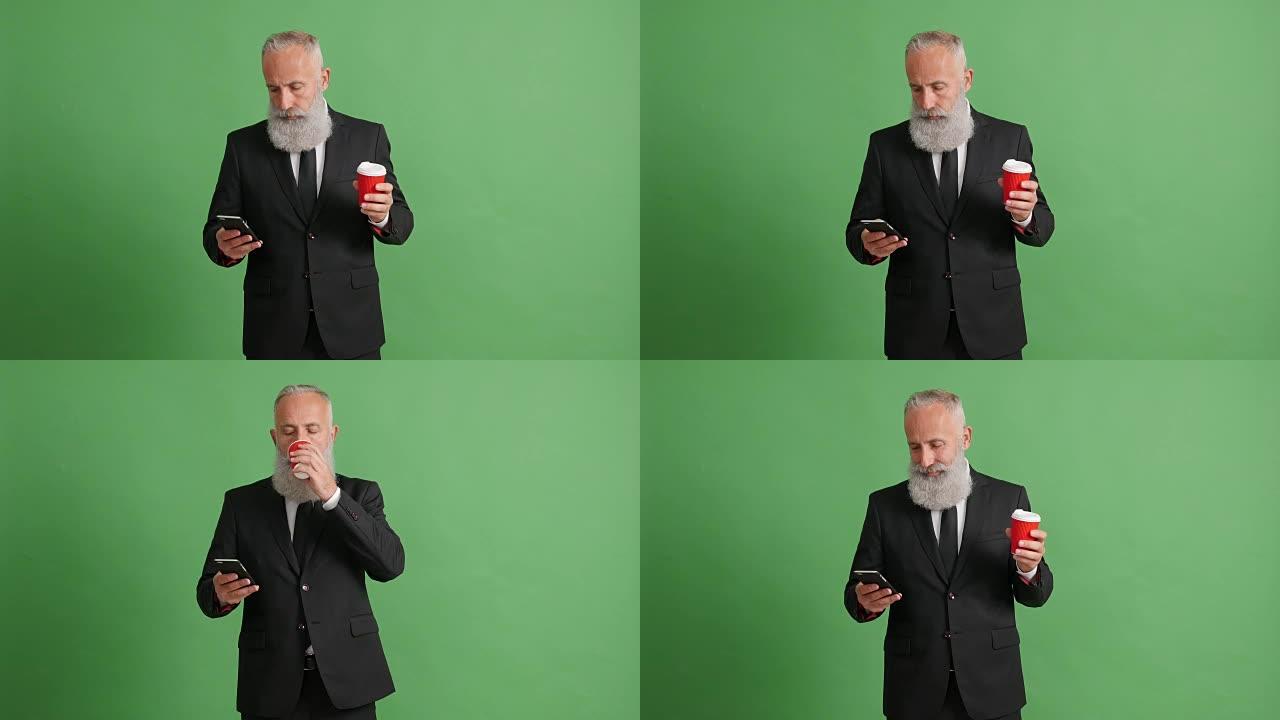 大胡子的成年商人正在绿色背景上使用智能手机